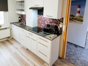 A modern kitchen with white cabinets, a black countertop, and a coffee maker.