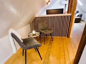 A modern room with two grey chairs, a small round table with a candle, and a wooden slatted partition.
