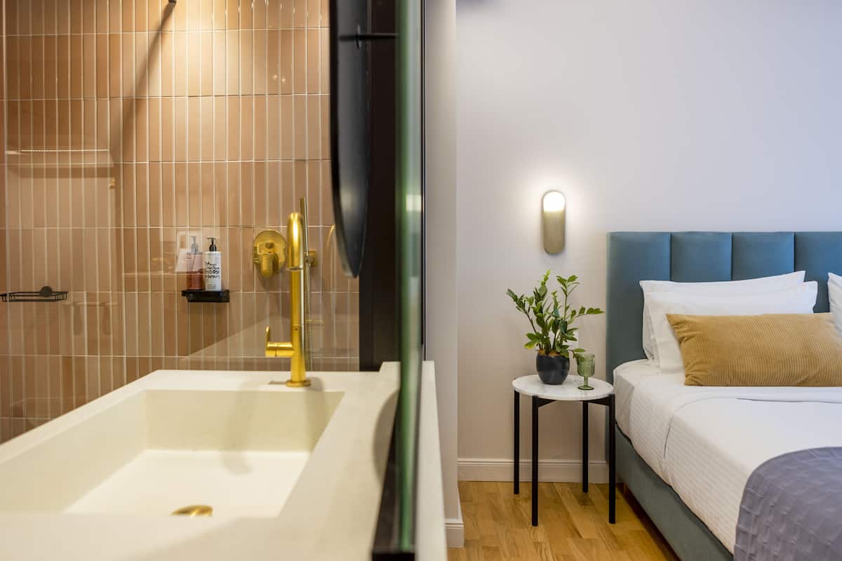 Ein modernes Badezimmer mit einer Badewanne, einer Dusche und einem kleinen Nachttisch mit einer Pflanze.