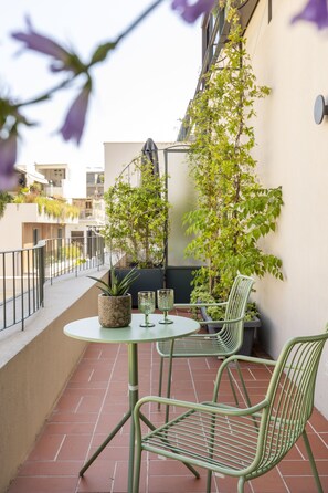 A small outdoor patio with a round table and two chairs, surrounded by potted plants and a view of neighboring buildings. - L'Avventura Athens (Athens)