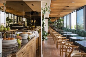 A restaurant with a long counter, wooden chairs, and green cushioned seating. - L'Avventura Athens (Athens)