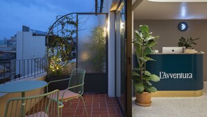 A modern reception desk with 'L'Adventure' signage, a glass door entrance, a small balcony with a chair and table, and a potted plant. - L'Avventura Athens (Athens)