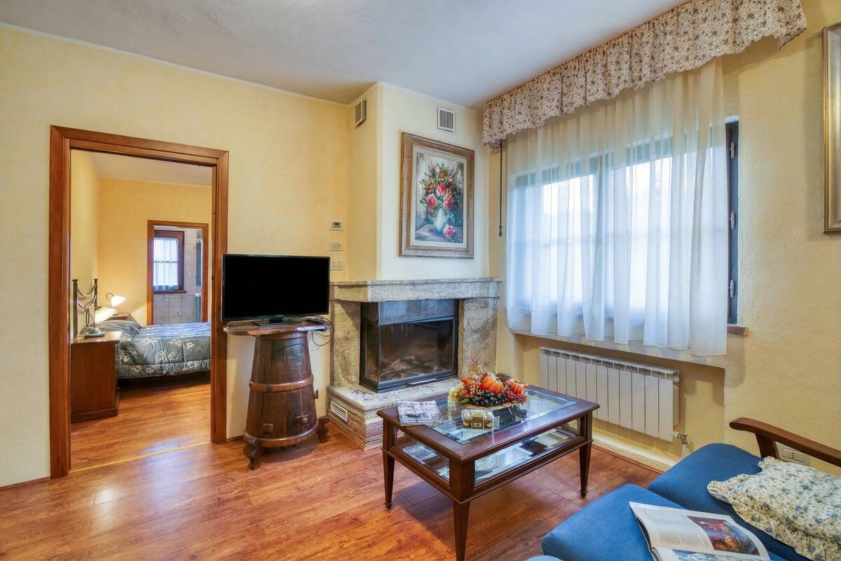 A living room with a fireplace, a television, a sofa, and a dining table.