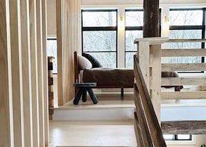 Una stanza con un letto, un tavolino e una finestra vista alberi.