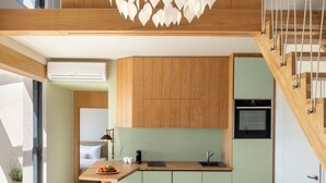 A modern kitchen with a wooden ceiling, a built-in oven, and a dining area with stools. - Greenstone Villas (Corfu)