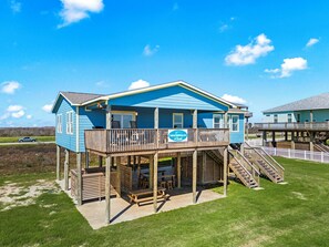 A two-story beach house with a deck, outdoor seating, and a staircase leading to the upper level. - Beachfront  | Expansive Deck, Grill & Ocean Views (Gilchrist)