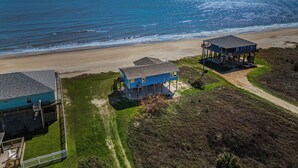 A coastal property with a beach house, a separate structure with a balcony, and a fenced yard. - Beachfront | Expansive Deck, Grill & Ocean Views (Gilchrist)