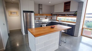 A modern kitchen with a central island, stainless steel appliances, and a view of the outdoors.