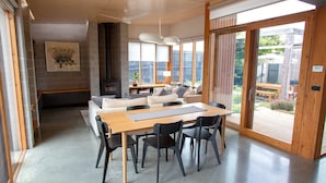 Een moderne woonkamer met een houten eettafel, zwarte stoelen, een bank en een open haard.