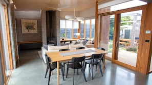 A modern living room with a wooden dining table, black chairs, a sofa, and a fireplace.