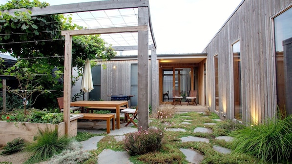 A modern outdoor patio with a wooden pergola, a table, and chairs.