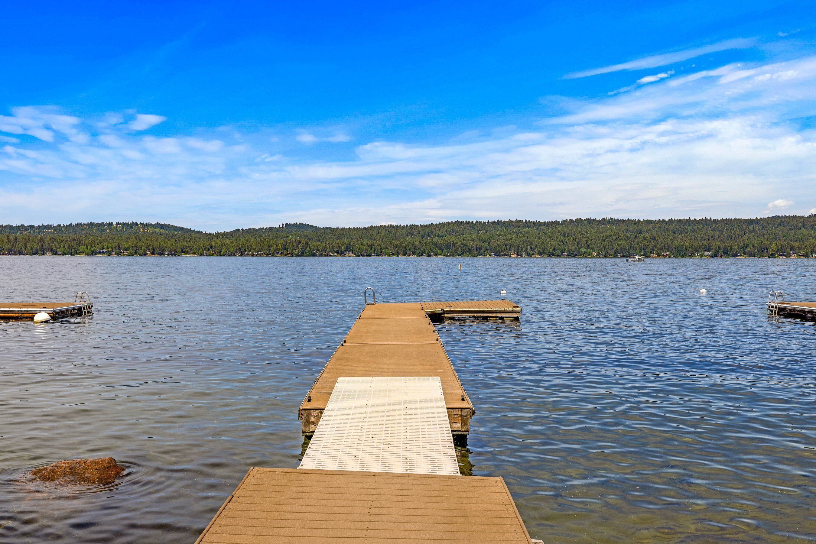 A wooden pier extending into calm water with a clear sky above.