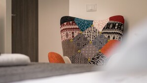 En stol med et mønstret hyndebetræk og en grå pude.