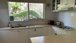A kitchen with a window, a sink, a stove, and cabinets.