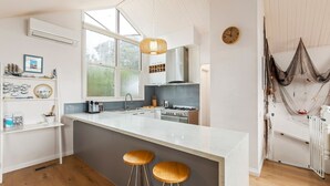 Une cuisine moderne dotée d’un grand îlot central, de meubles blancs et d’un luminaire suspendu.