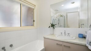 A modern bathroom with a bathtub, a large mirror, and a sink. - Private Hideaway - Point Lonsdale (POINT LONSDALE)
