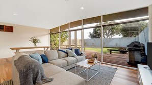 A modern living room with a sectional sofa, a coffee table, and a TV stand. - The 20th Hole - Point Lonsdale (POINT LONSDALE)