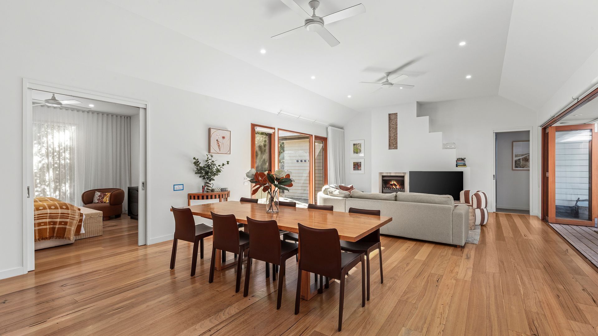 A spacious living area with a wooden dining table, sofas, and a fireplace.