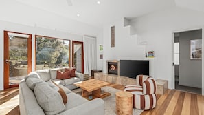 A modern living room with a sofa, coffee table, and striped armchair. A fireplace and TV are visible.