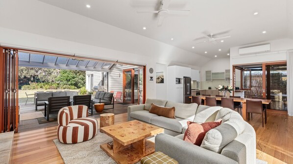 A spacious living room with a sofa set, a coffee table, and a dining area with a table and chairs.