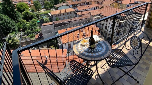 A balcony with a round table, two chairs, and a bottle of wine. - Romantica Suite modern apartment in Verbania Intra (Verbania)