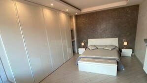 A modern bedroom with a large bed, bedside tables, a wardrobe, and a seating area. - Romantica Suite modern apartment in Verbania Intra (Verbania)