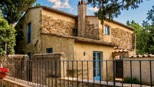 Un edificio de piedra con un balcón, una puerta y una ventana.