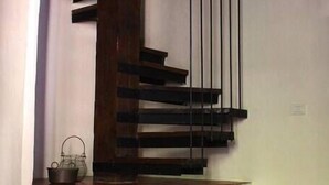 Una escalera de caracol con escalones de madera y barandillas negras, que conduce a un piso superior.