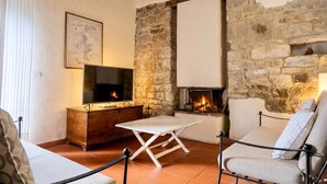 A cozy living room with a stone fireplace, a flat-screen TV, and a comfortable seating area.