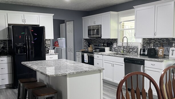 A modern kitchen with white cabinets, a black refrigerator, a microwave, and a granite countertop. - Norris Lake-Ride Royal Blue-Tackett Creek (Jacksboro)