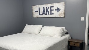 A bedroom with a bed, a nightstand, a wall-mounted sign, and a patterned rug. - Norris Lake-Ride Royal Blue-Tackett Creek (Jacksboro)