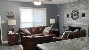 A modern living room with a brown leather sectional sofa, a granite countertop, and a ceiling fan. - Norris Lake-Ride Royal Blue-Tackett Creek (Jacksboro)