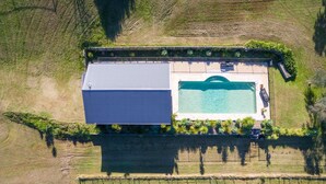 Vue aérienne d’une propriété comprenant une piscine, un grand bâtiment et des champs en terrasses.