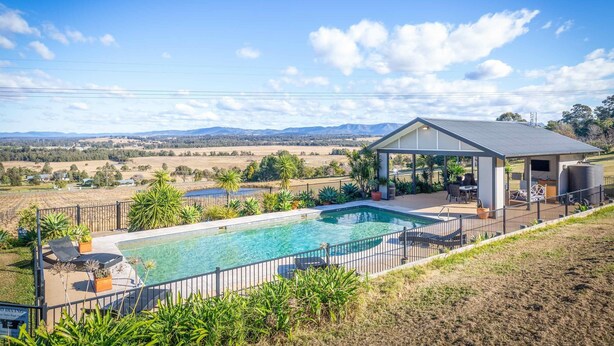 Une piscine dotée d’un patio couvert, entourée d’une clôture et d’une végétation luxuriante.