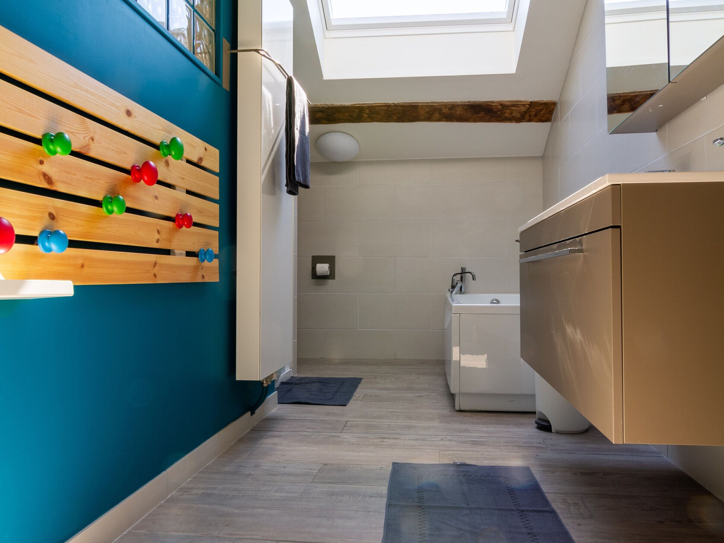 A modern kitchen with a wooden rack holding colorful balls, a sink, and a window above the countertop.