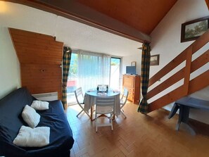Una stanza accogliente con un divano, un tavolo da pranzo, sedie, una TV e una scala.