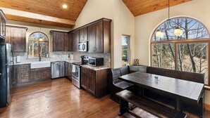 Una cocina con armarios de madera, horno empotrado y un comedor con banco.