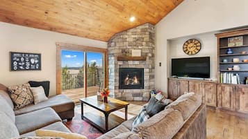 A cozy living room with a stone fireplace, a television, and a bookshelf.