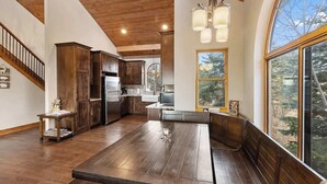 Una cocina amplia con armarios de madera, una mesa de comedor grande y vistas por un ventanal.