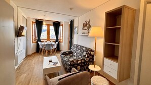 Una sala de estar acogedora con sofá, mesa de centro, mesa de comedor con sillas y lámpara.