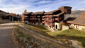 Un edificio grande de varios pisos con balcones, con montañas al fondo.