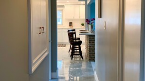 A hallway with a chandelier, a dining area with a chair, and a kitchen in the background. - The Grand Gorge Villa-With Yard& Parking (Niagara Falls)
