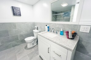 A modern bathroom with a toilet, sink, and mirror. There is a sign on the wall with bathroom instructions.