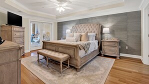 A bedroom with a large bed, a bench, a dresser, a nightstand, and a ceiling fan. - Great Family Condo with Pool Views! Pool Access (Tybee Island)