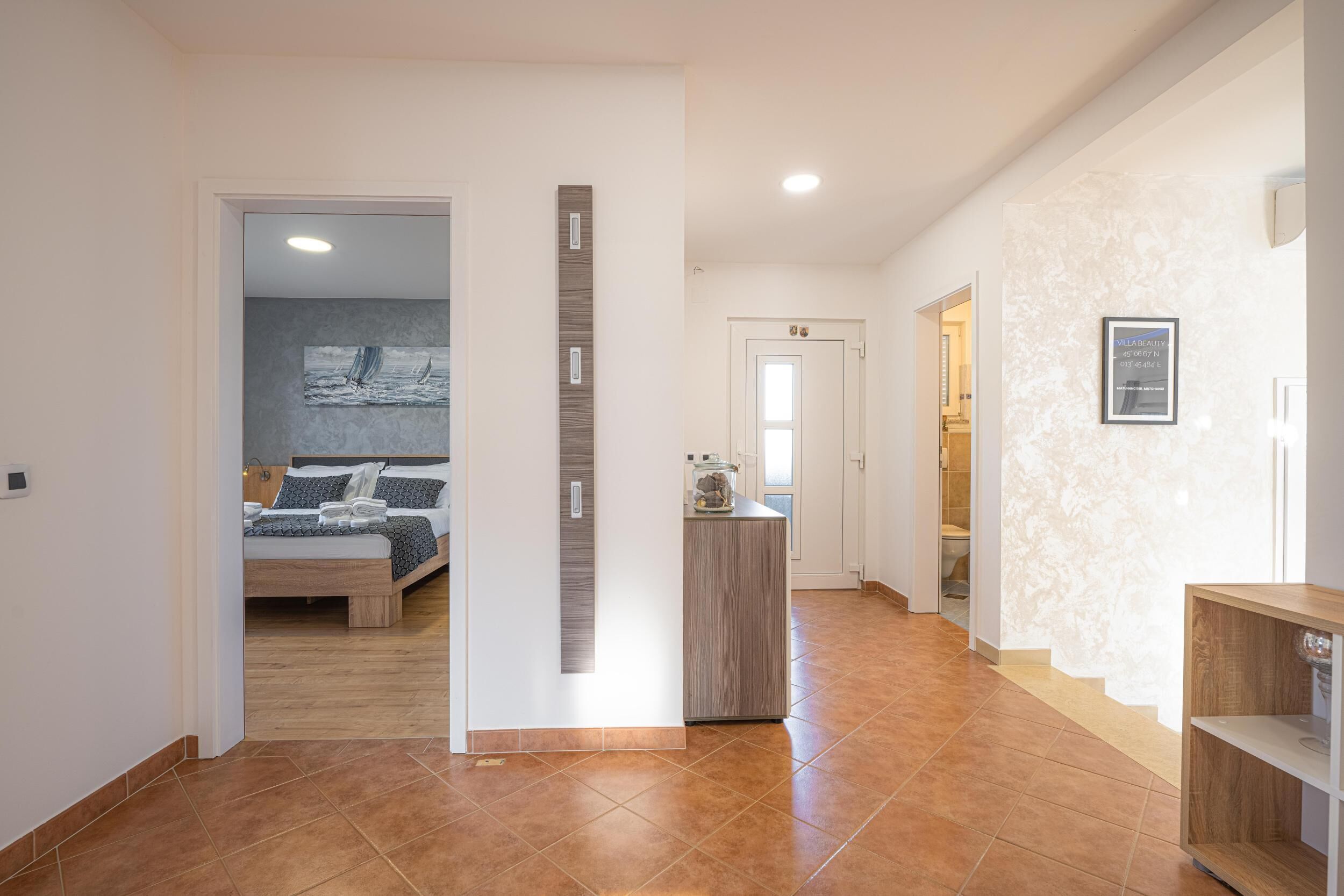 A modern hotel room with a bed, a small desk, and a bathroom visible through an open door.