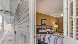 A bedroom with a bed, bedside table, lamp, and a view of the outside balcony.