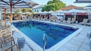 A swimming pool with lounge chairs and umbrellas, surrounded by a tiled deck.