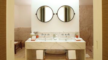 Une salle de bain avec deux miroirs, un lavabo et une chaise en osier.