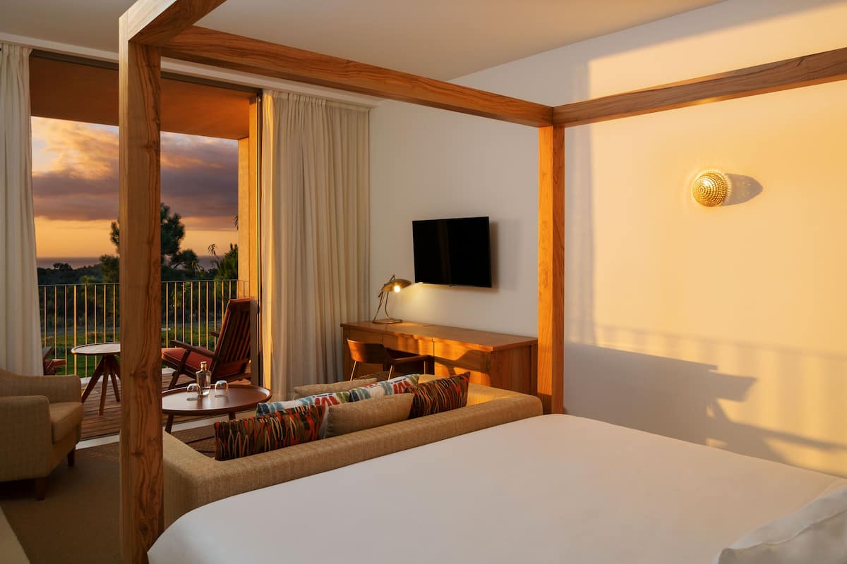 A hotel room with a bed, a desk, a chair, and a TV.