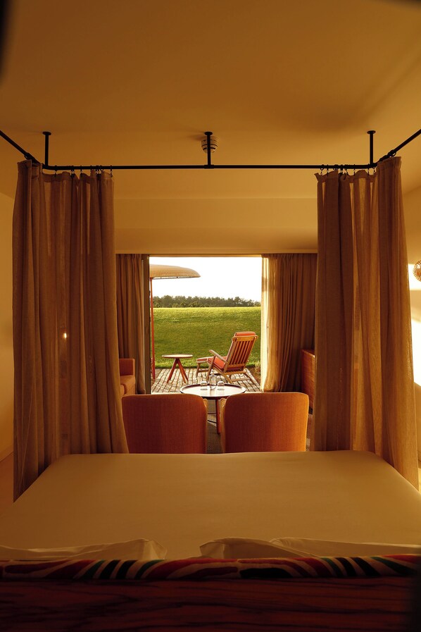 A hotel room with a large bed, curtains, and a view of the outdoors. - Praia do Canal Nature Retreat Small Luxury Hotels of the World. (Aljezur)
